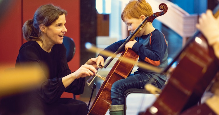 Musiker hjelper et barn å spille cello.