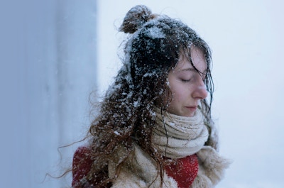 En kvinne med lukkede øyne og snø i håret