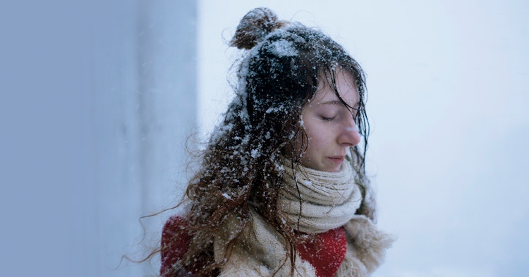 En kvinne med lukkede øyne og snø i håret